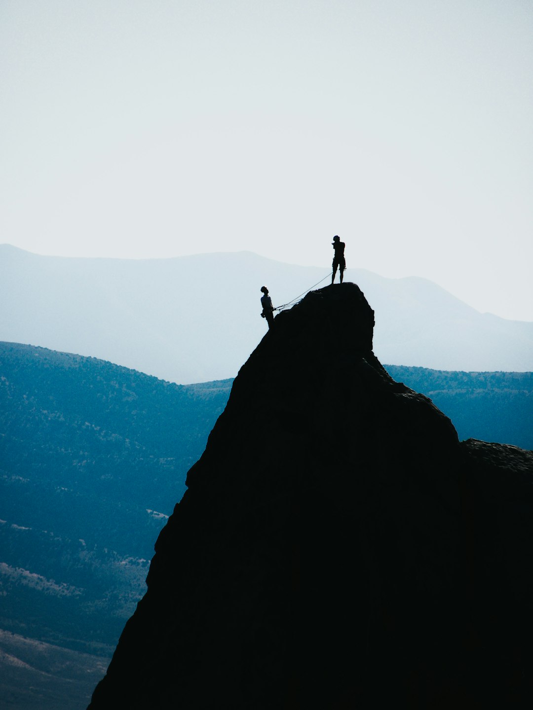 silhouette-of-two-people-standing-on-mountain-during-daytime-lvvfcmmwwlk